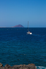 A pleasure sailboat sails by motor near the coast