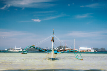 Traditional banca boat in clear water at sandy Corong Beach in El Nido, Philippines. Low angle view