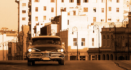 A classic car driving in a street in Havana. These old and classic cars are an iconic sight of the...