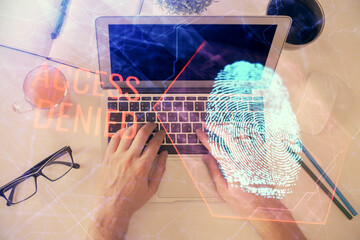 Double exposure of man's hands typing over computer keyboard and finger print hologram drawing. Top view. Personal security concept.