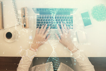 Double exposure of woman hands working on computer and DNA hologram drawing. Top View. Medical...
