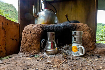 Wood burning stove with kettle, teapot and mugs in a wooden house.