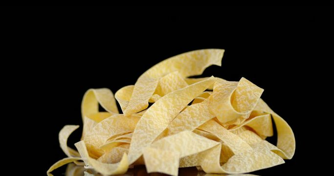 Dry pappardelle pasta on the table slowly rotates.