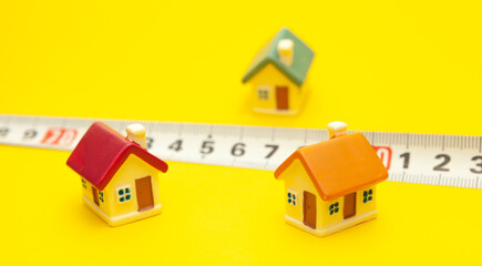 Measuring tape and colored houses on a yellow background