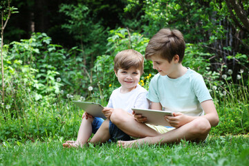 Two brothers play a touchpads on the grass