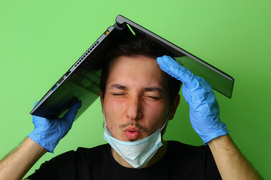 man holds a laptop on his head metaphorically depicting the roof of a house. Emotion of fatigue. Work from home concept