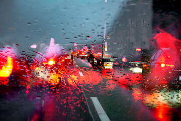 Motorway traffic jam caused by an accident on a wet road. View through a rainy windscreen to the...