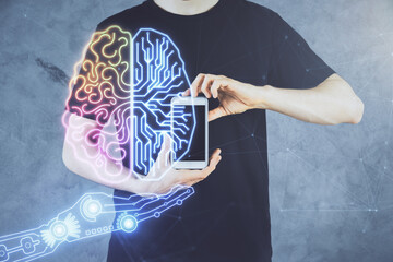 Double exposure of man's hand holding and using a digital device and brain hologram drawing. Data...