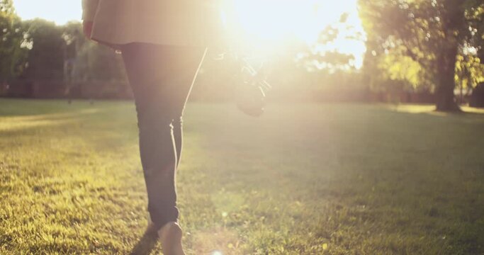 A woman taking a barefoot walk on the beautiful, green grass - close up