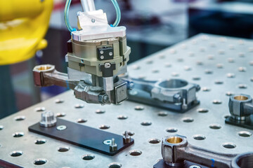 The hand of an industrial robot moves a detail of a connecting rod