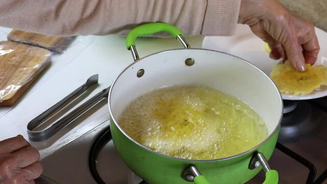 Frying traditional plantain smashed pieces called patacones or tostones