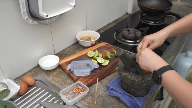 Woman sqeeze lime into motar.