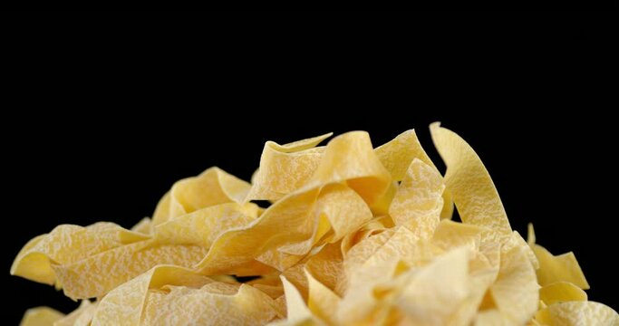 Homemade pappardelle pasta dry on the table slowly rotates.