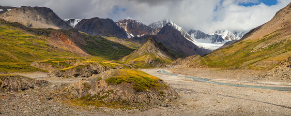 Panoramic view, mountain valley. River, treeless slopes. Severe weather, natural light.