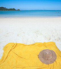Yellow towel with hat on beach and sea