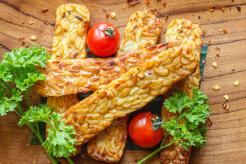 Fried tempeh or tempe (traditional Indonesian soy product), cherry tomatoes and parsley on wooden...