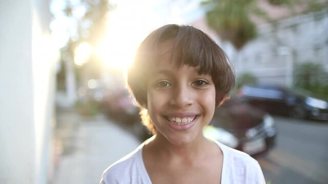 Child portrait of multicultural descent smiling to camera. Happy mixed race diverse young boy face during golden hour time