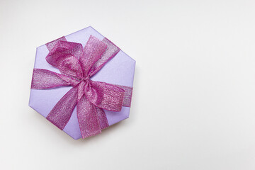 A beautiful lilac hexagon box of present with ribbon and bow on the white background. Flat lay. Place for text