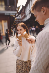 newlywed couple eating ice cream from a cone on a street in Shanghai near Yuyuan. Couple take a break for a snack while visiting China. husband and wife sharing ice cream outisde of a food hall