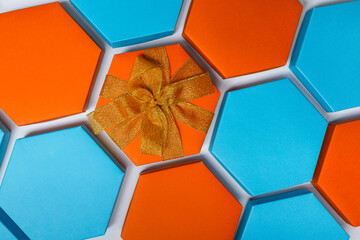 A close up beautiful blue and orange hexagon gift boxes on the white background. One of them with bright ribbon and bow. Place for text. Empty boxes. Top view. Flat lay