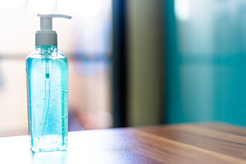 Blue alcohol hand sanitizer on wooden In the room at home background,Concept of Prevention of the spread of COVID-19 virus infection
