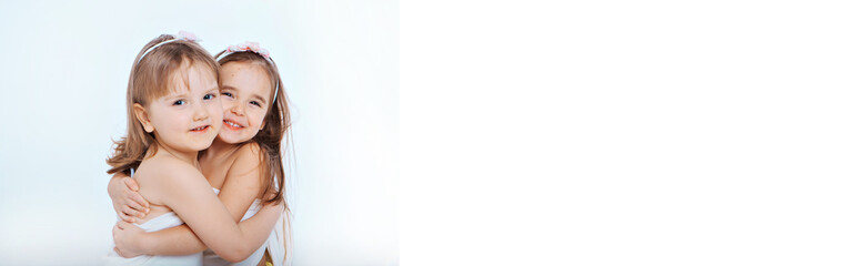 two little happy girls smiling on white background. Portrait of children hugging. The concept of relationships in the family, friends, sisters, couple in love. Copy space