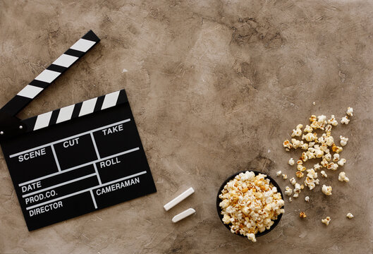 Filmmaking concept. Movie Clapperboard. Cinema begins with movie clappers. Movie clapper board on a textural background and popcorn.