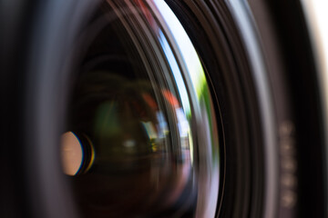 Close-up macro shot of a camera lens with reflections on multi colored light of glass