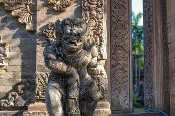 Traditional guard demon statue carved in light grey stone, Denpasar, Bali, Indonesia