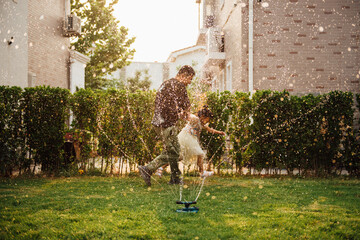 A pair of Asian father and daughter playing with water in the yard