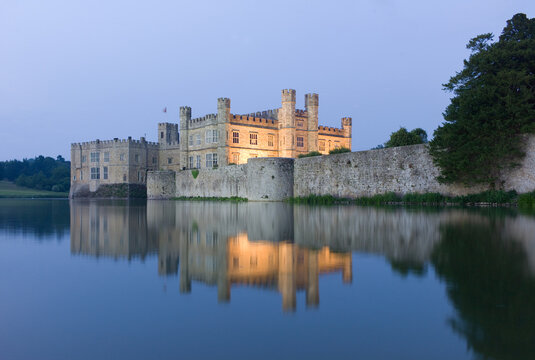 Famous illuminated Leeds Castle In the United Kingdom mirrored in surrounding Water early in the evening
