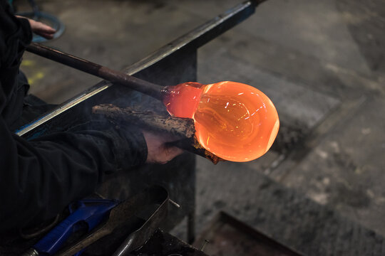 Spinning iron tube with which glass is blown, with a red-hot lump of liquid glass, one of which is formed a wine glass with a wad of wet newspaper in a glassworks in Kosta, Sweden