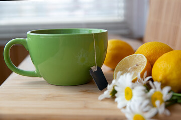 morning Cup of black tea with lemons and chamomile flowers on a wooden table