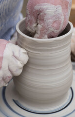 Close view on hands working on pottery wheel with clay