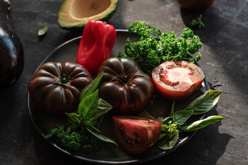 Bio organic vegetables on black chalkboard background, healthy raw vegan food concept. Shallow depth of field