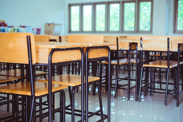 Lecture room, School empty classroom with desk chair iron wood for studying lessons in high school. No student in situation of Covid-19 disease outbreak result in inability organize teaching learning