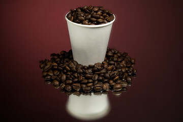 Paper cup of coffee and coffee beans on red