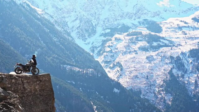 A man standing with his bike and smoking at the edge of the cliff at suicide point , kalpa , himachal pradesh
