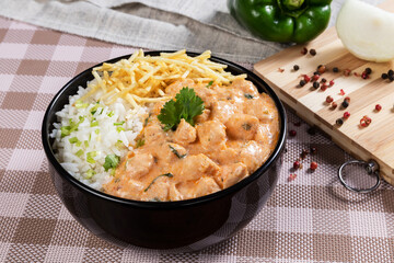 Chicken stroganoff in bowl with straw potato