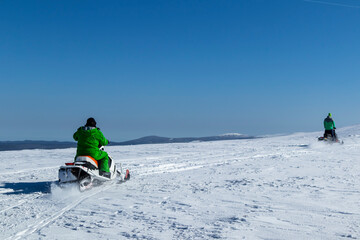Rider on the snowmobile in the mountains ski resort. A man is riding snowmobile in mountains