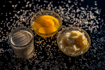 Close up shot of ayurvedic method or calcium supplement on the black surface consisting of raw eggs, milk, and ghee or clarified butter along with some sugar as a sweetener.