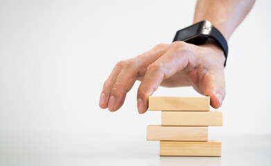 conceptual businessman fingers arranging  wooden blocks