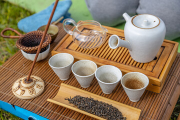 Tea ceremony at the outdoors camping site. Still life of appliances for tea consumption laid down on the tea table with tea and incense sticks.