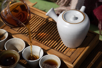 Tea ceremony at the outdoors camping site. Pouring some tea