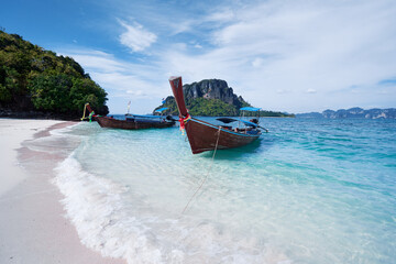 Fototapeta na wymiar Beautiful landscape with traditional longtail boats, rocks, cliffs, tropical white sand beach. Traveling by Thailand.