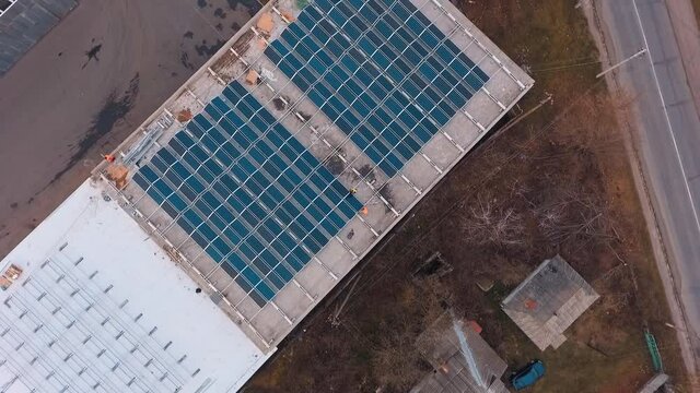 Construction of modern solar farm on roof. Workers build new solar station. Photovoltaic solar panels generate clean energy from the sun. Aerial view.