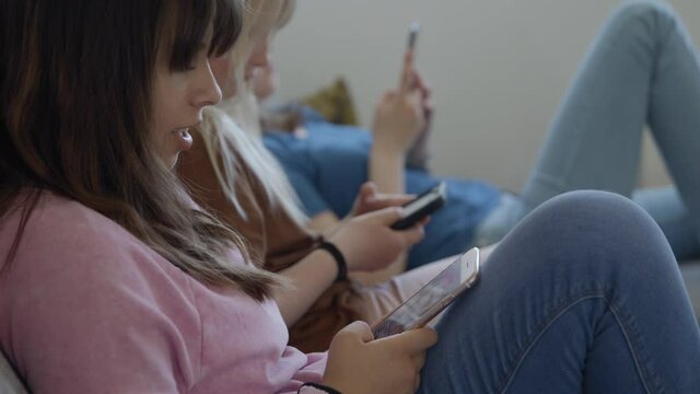 Close up of three young girls watching TikTok videos on their phones
