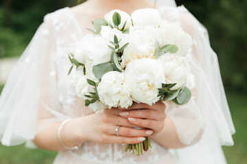 luxurious bouquet in the hands of the bride in a wedding dress and veil, rings
	
