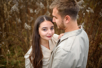 Close up of a beautiful young happy couple in love embracing while spending time in the autumn park