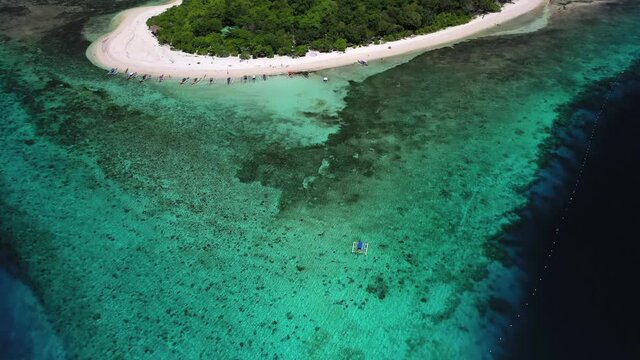 Banca boat approaching Mantigue Island in the Philippines, tilt down aerial